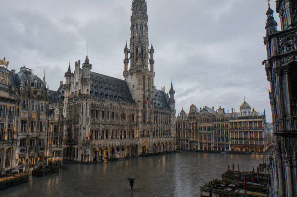 Ornate gothic tower rising above a cobblestone square lined with decorated facades