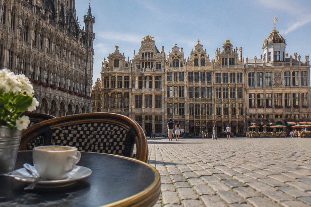 Cobblestone square with ornate gilded guild buildings under a daylight sky