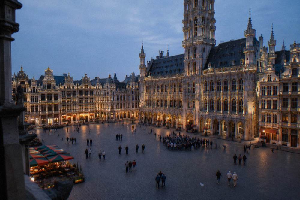 Crowd of visitors gathered on a cobblestone square beside a gothic tower