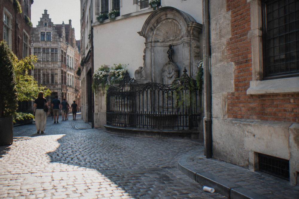 A narrow Brussels street corner with the small fountain statue and stone buildings on each side