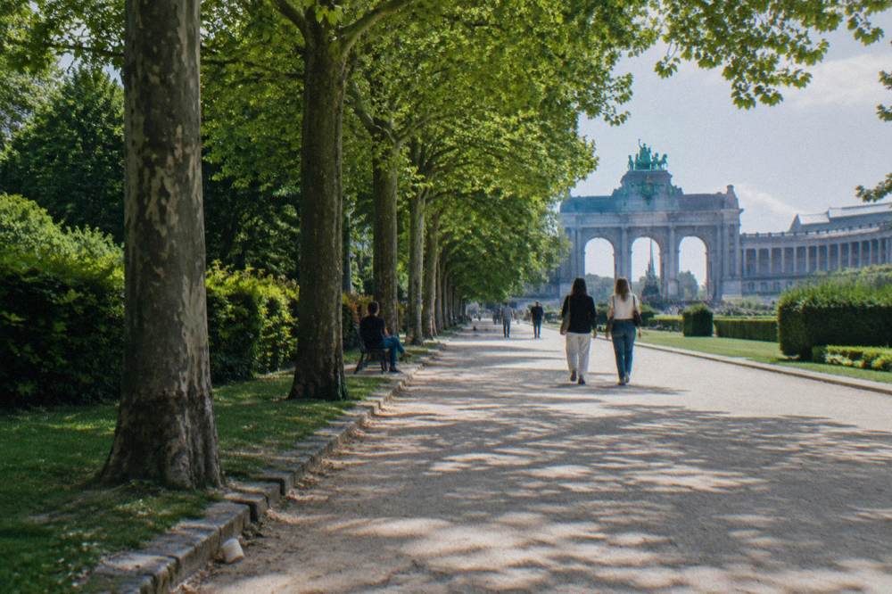 Tree-lined paths and the Cinquantenaire arch in the public park under an open sky