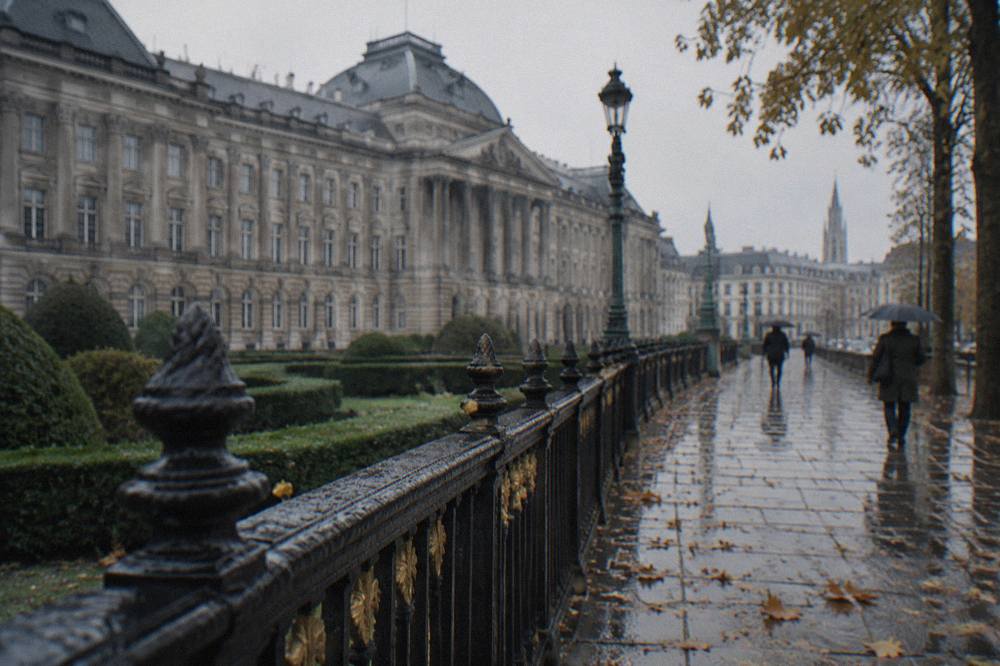The long classical facade of the Royal Palace of Brussels with its central columned entrance and row of flags