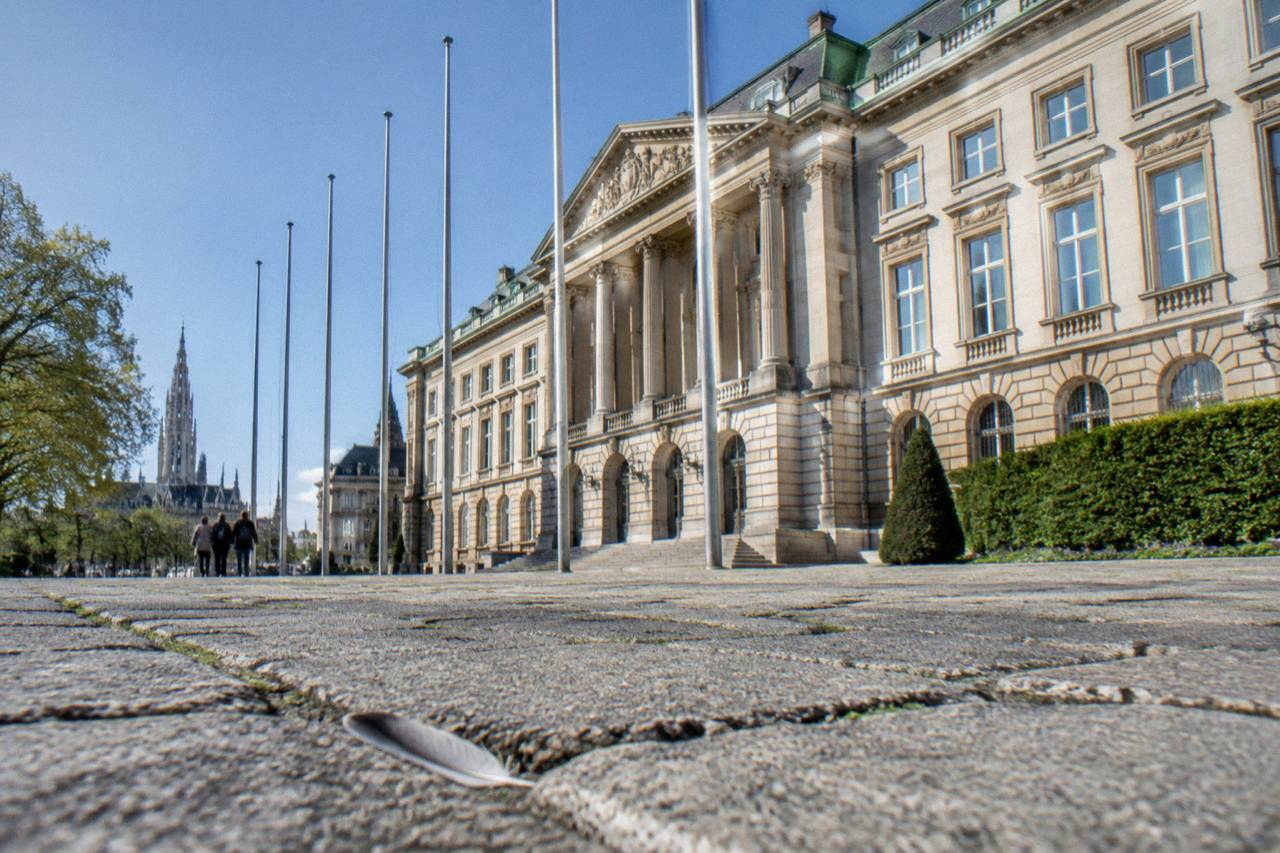 The facade of the Royal Palace of Brussels seen from the square in front, with clear sky above the columns and flagpoles