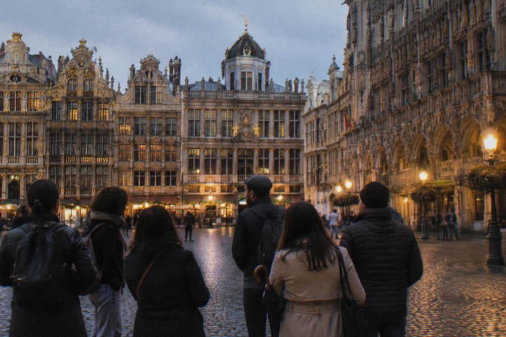 A guided walking group gathered on a cobbled square in Brussels beside historic guildhalls
