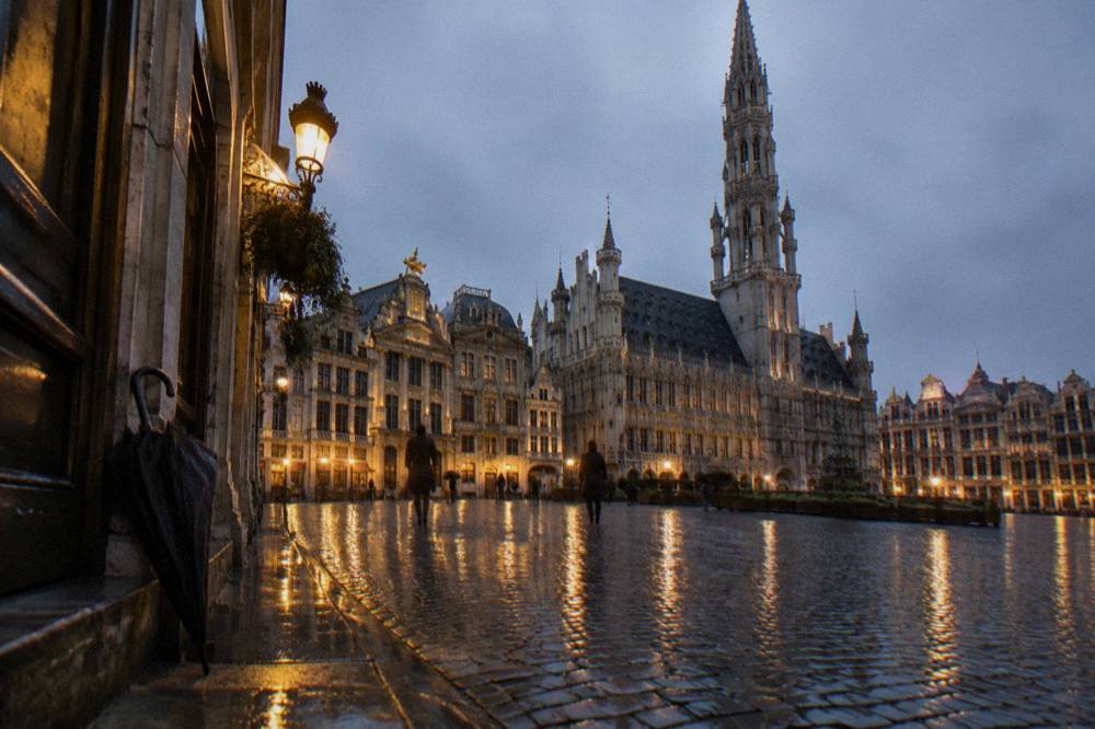 Cobblestone square in Brussels with ornate guild house facades and a gothic tower