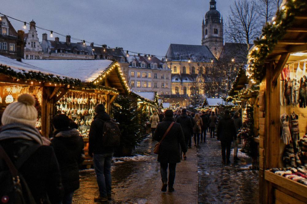 Festively decorated wooden market chalets along a city street with string lights overhead