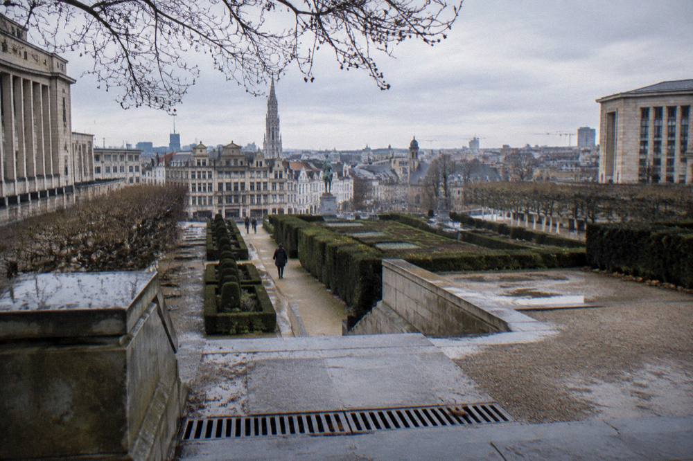 A terraced public garden with clipped hedges overlooking city rooftops on a winter afternoon
