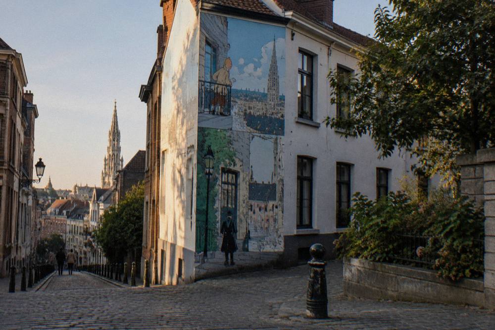 A tall comic strip mural covering the side wall of a corner building on a Brussels street