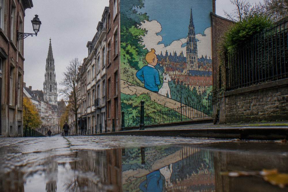 A painted mural of comic characters on a narrow Brussels side street