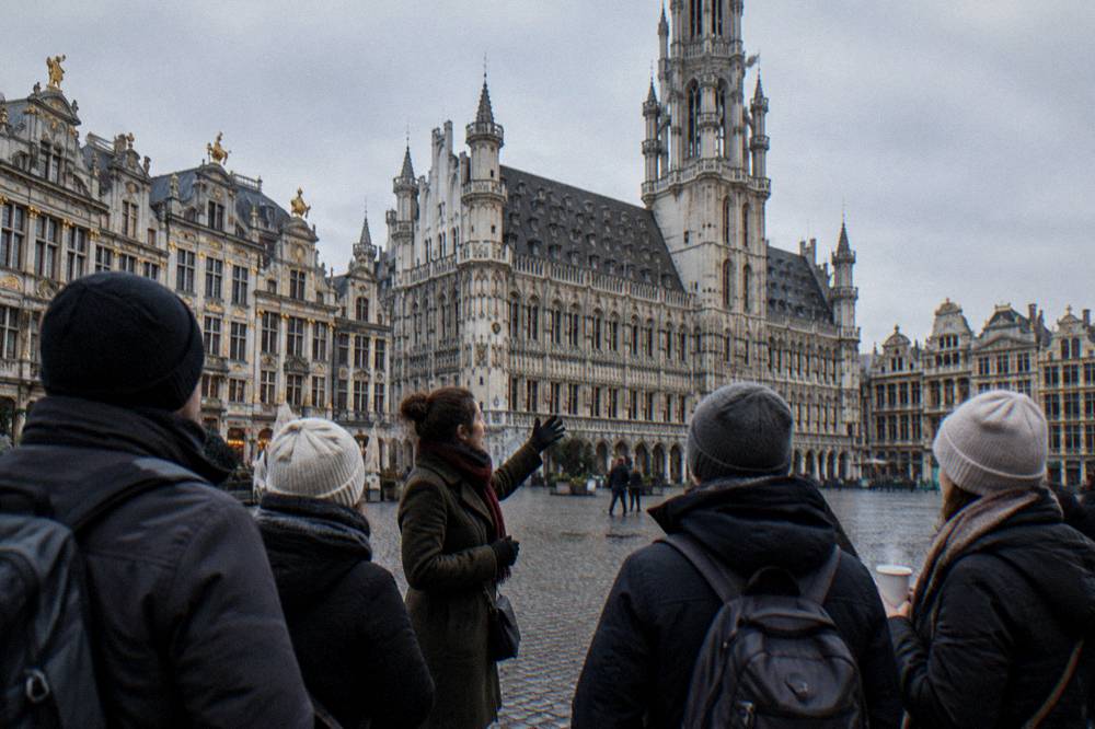A tour guide speaking to a small group of visitors in a Brussels square in winter daylight