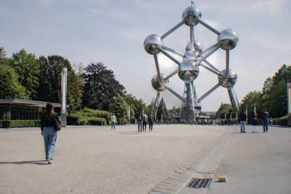 Steel sphere structure rising above a plaza with visitors standing at a distance