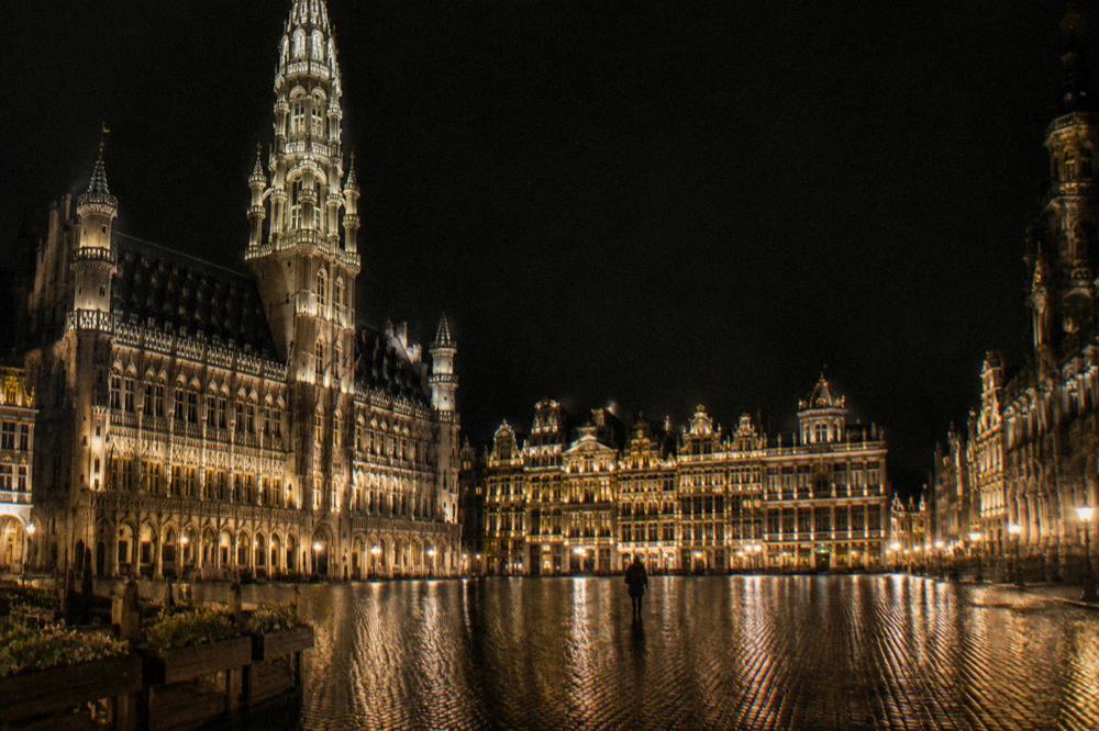 Illuminated guild house facades and the Town Hall tower lit up at night on the Grand-Place