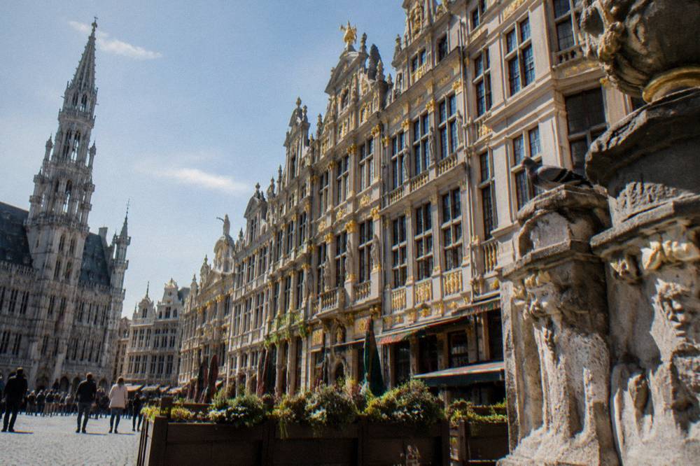 Rows of ornate gilded guild house facades lining one side of the square